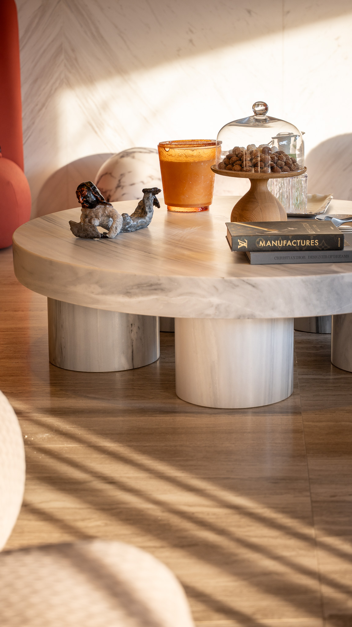 Dusit Suites Athens, sunlit styled coffee-table vignette with marble pedestal and amber glass
