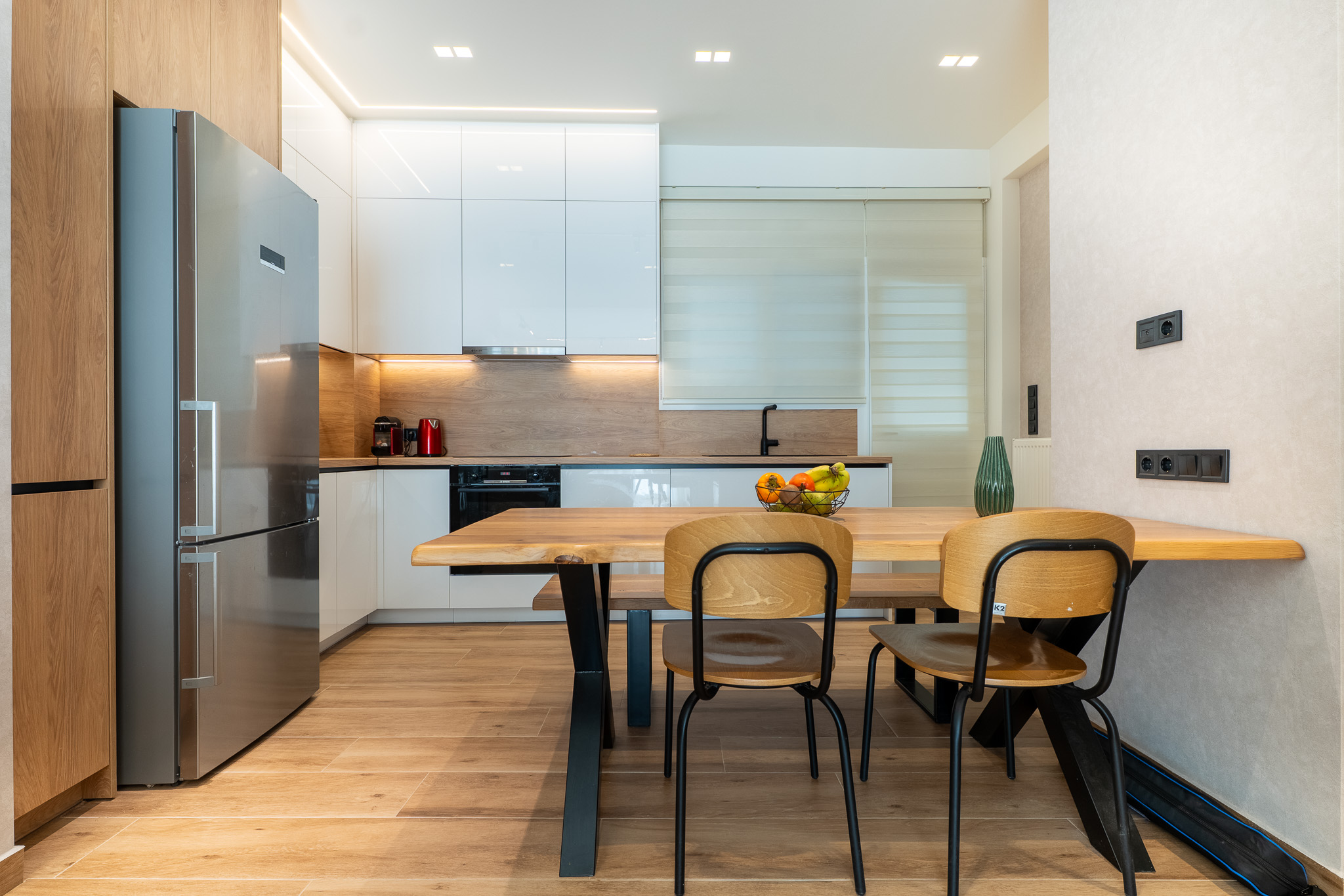 A&K Chorothetisis, white gloss L-kitchen with oak backsplash and live-edge dining table
